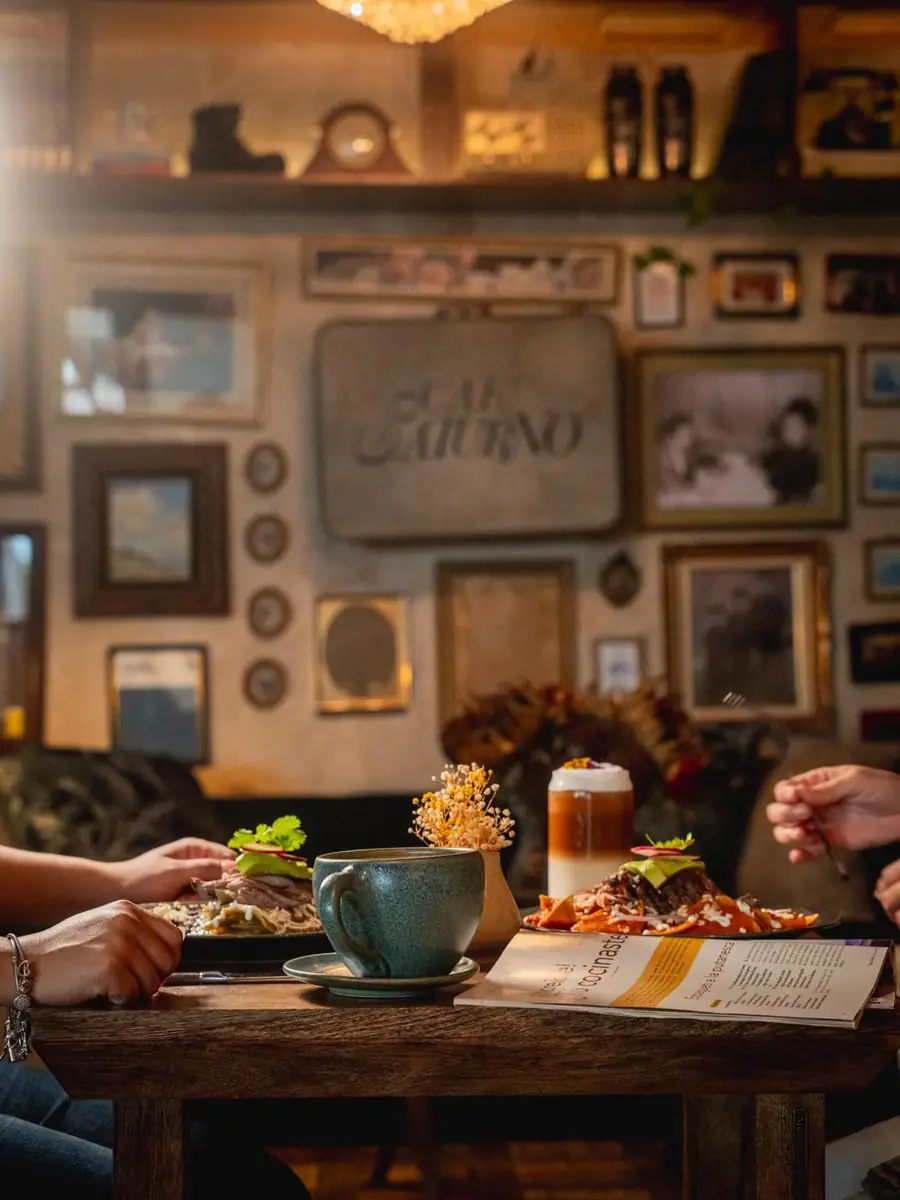 Mesa con platillos y bebidas frente a una pared de cuadros